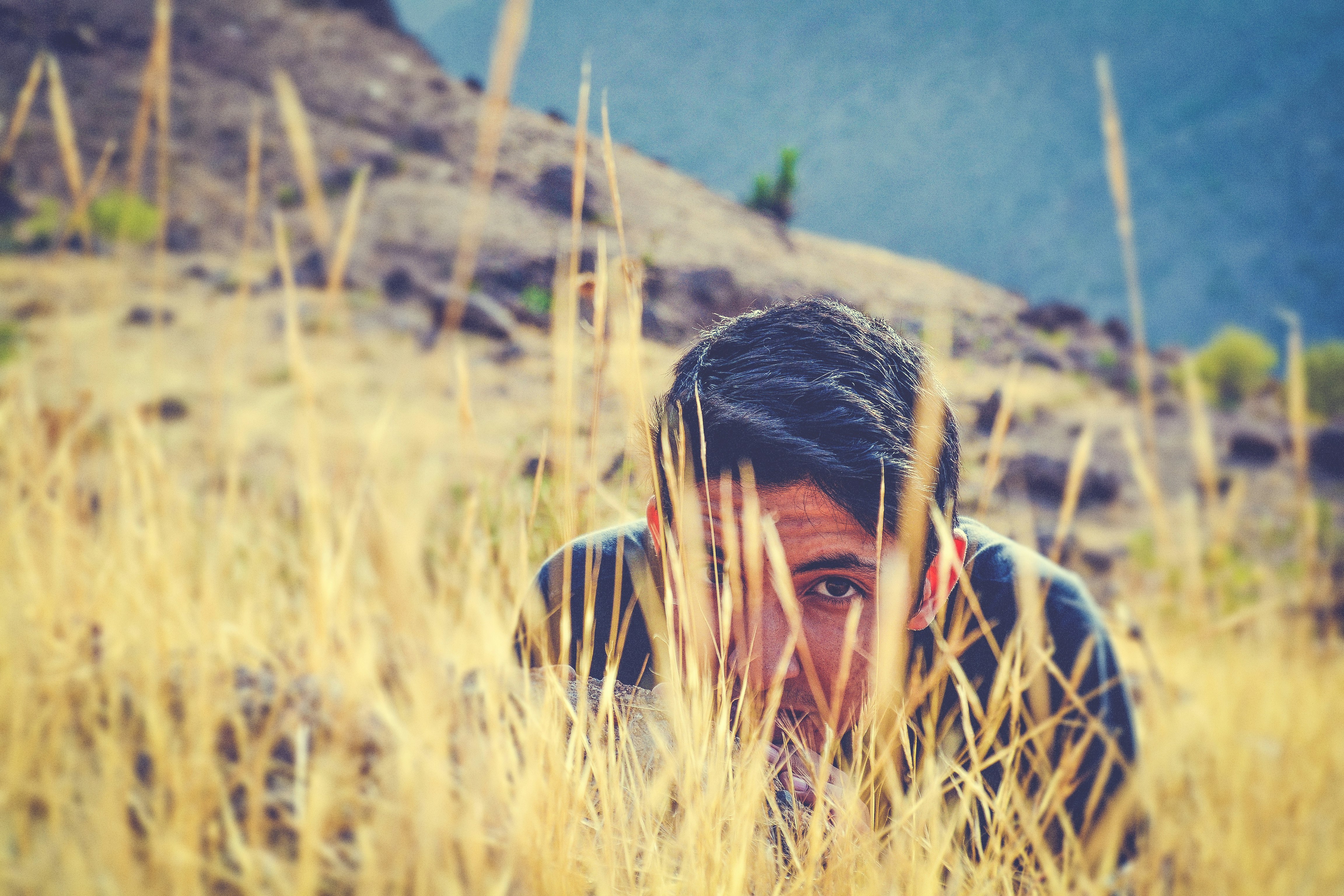 man wearing black shirt hiding on green grass field at daytime